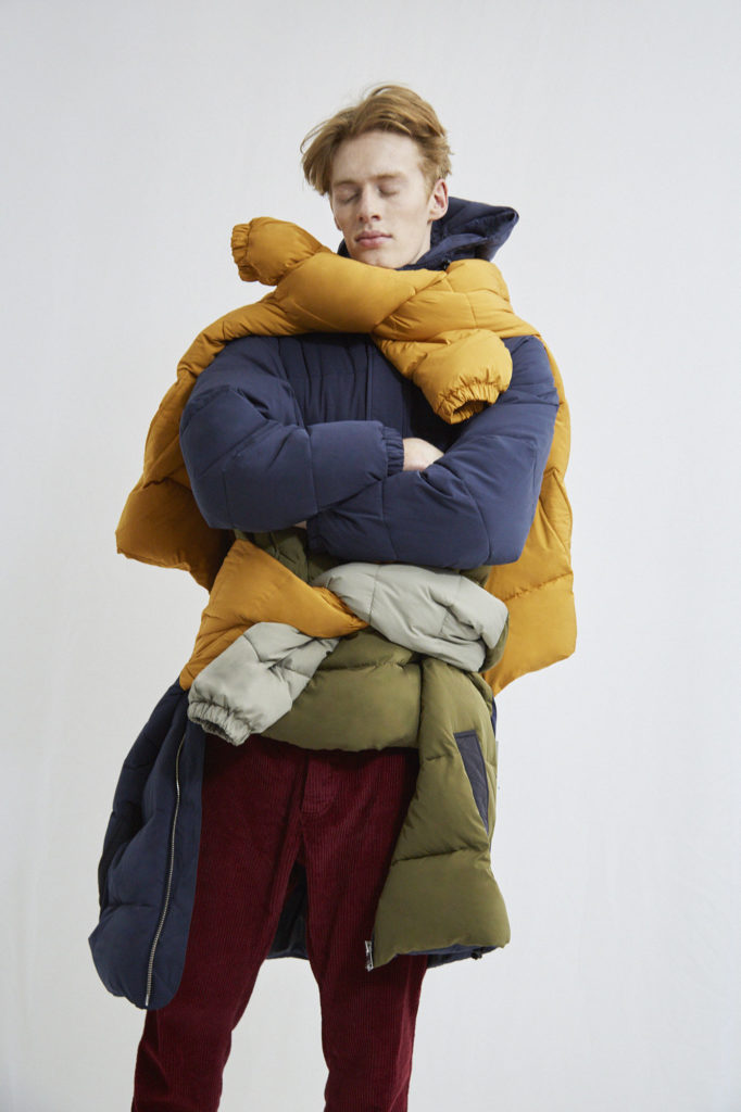 Ein männliches Model trägt mehrere Winterjacken übereinander